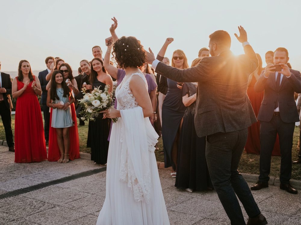 Pareja bailando rodeada de invitados al atardecer